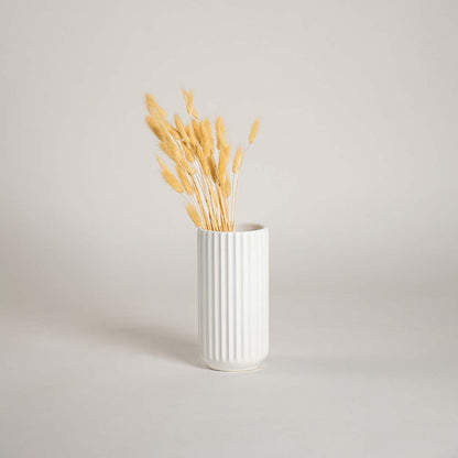 White ribbed ceramic vase placed in a soft minimal lifestyle scene adding a clean modern touch with its simple vertical textured design.