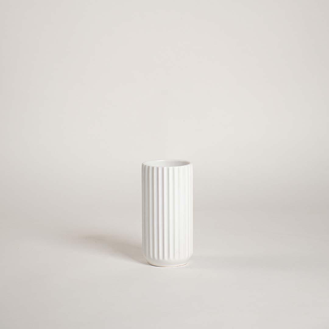 Minimal white ceramic vase showcased on a bright background with a clean ribbed design giving a simple modern decorative feel.