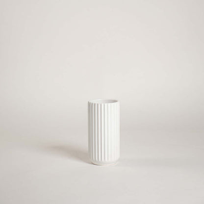 Minimal white ceramic vase showcased on a bright background with a clean ribbed design giving a simple modern decorative feel.