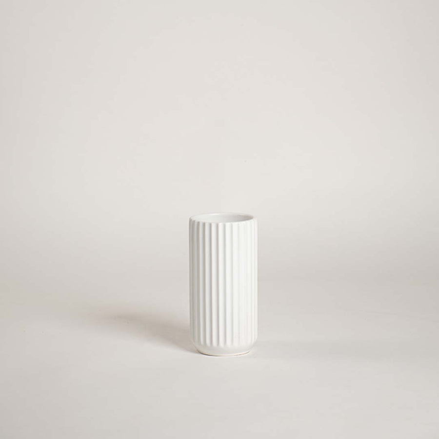 Minimal white ceramic vase showcased on a bright background with a clean ribbed design giving a simple modern decorative feel.