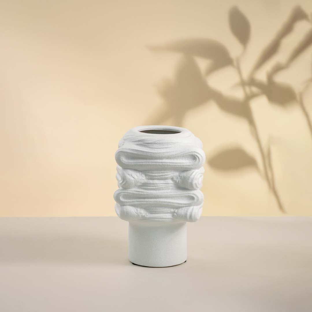 Elegant white ceramic vase placed on white background showcasing intricate surface texture and modern artistic shape.