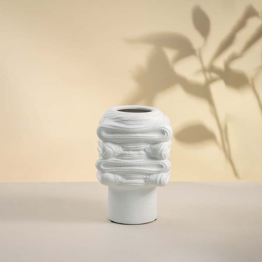 Elegant white ceramic vase placed on white background showcasing intricate surface texture and modern artistic shape.