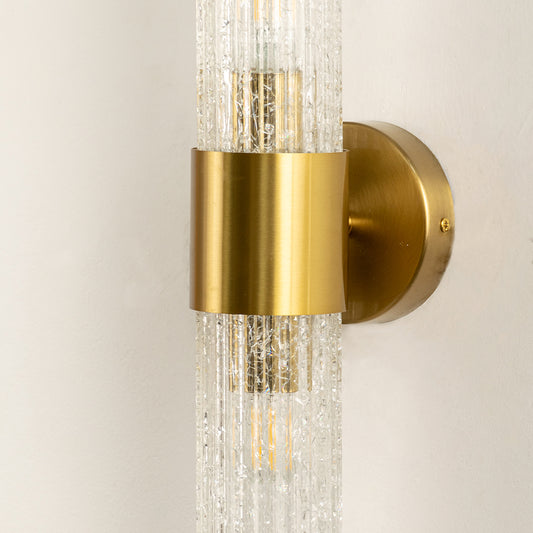 Closeup of gold metal wall light with textured crystal shade for elegant bedroom hallway and luxury home decor.