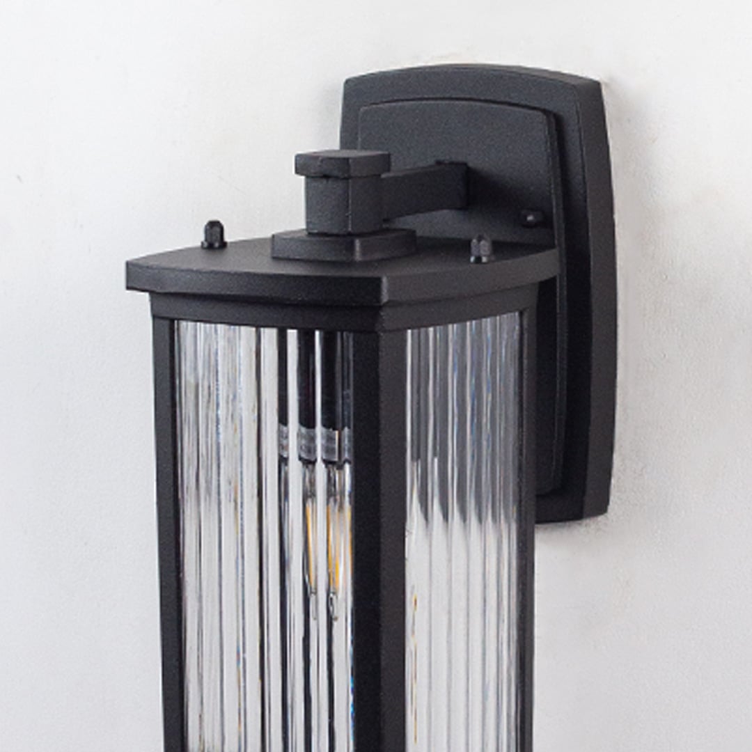 Closeup of outdoor wall light with ribbed glass design and black frame perfect for stylish home exterior illumination.