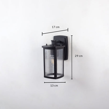Outdoor wall light with ribbed glass and black frame shown on white background with 29 cm height 17 cm width 13 cm depth.