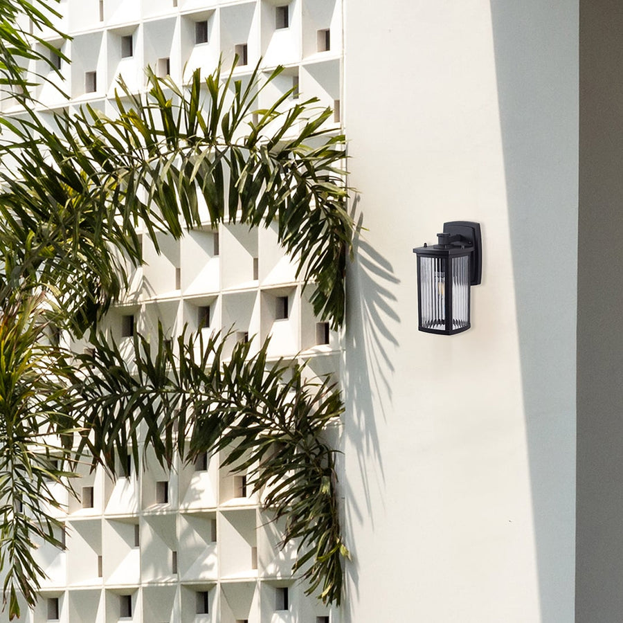 Outdoor wall light mounted on white exterior wall with green plants creating a modern and elegant home outdoor lighting setup.