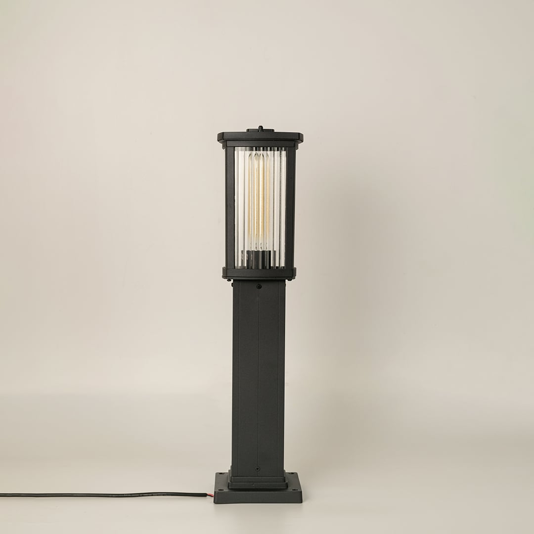 Black outdoor bollard light with ribbed glass shown with light off on a white background displaying its clean vertical structure and modern outdoor style.