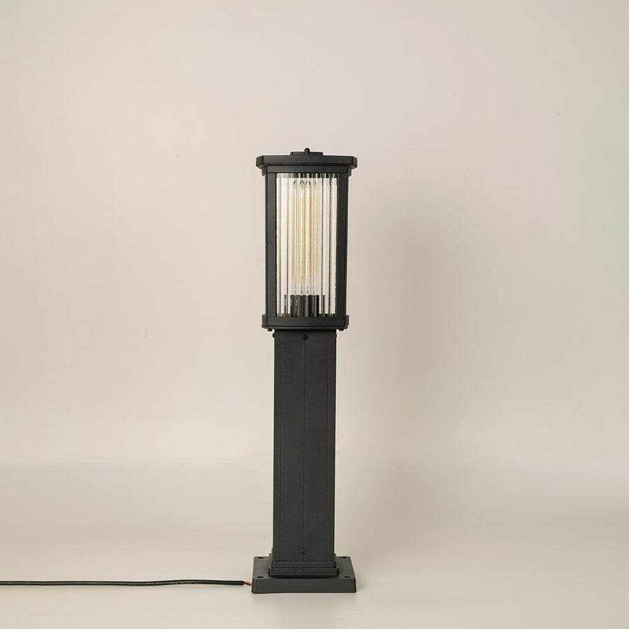 Black outdoor bollard light with ribbed glass shown with light off on a white background displaying its clean vertical structure and modern outdoor style.