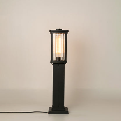 Modern black outdoor bollard light with warm glowing panels for stylish exterior decor use.