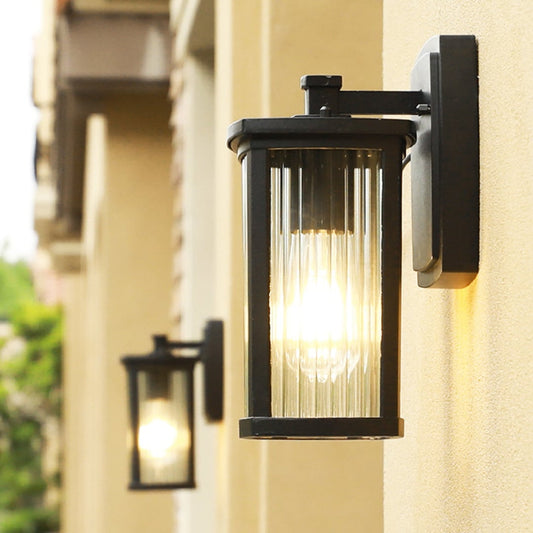 Modern outdoor wall light with black frame and ribbed glass glowing warmly on exterior wall perfect for entrance decor.