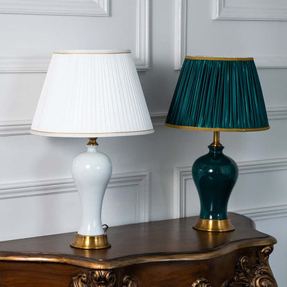 White and green ceramic table lamps turned off with gold bases and pleated shades displayed together showcasing color options for stylish living room or bedroom lighting.