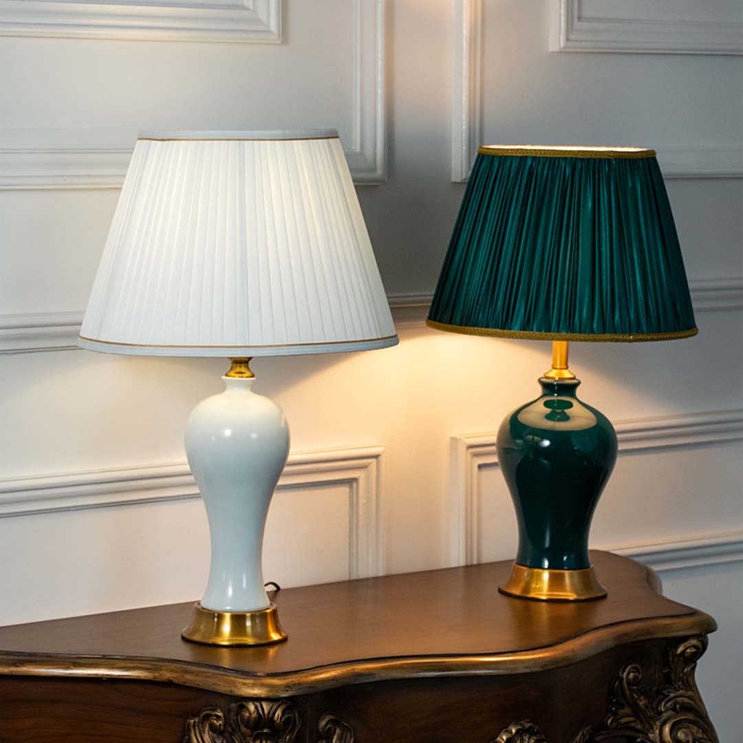 White and green ceramic table lamps with gold bases and pleated shades displayed together glowing showcasing color options for stylish living room or bedroom lighting.