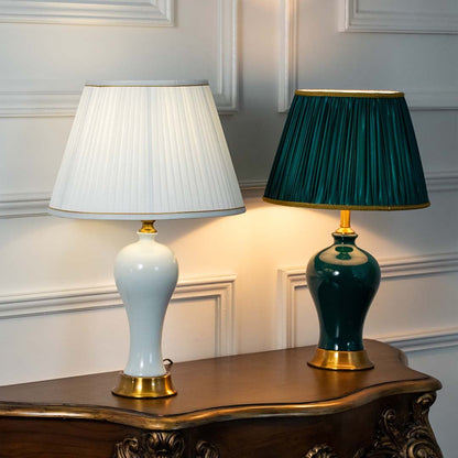 White and green ceramic table lamps with gold bases and pleated shades displayed together glowing showcasing color options for stylish living room or bedroom lighting.
