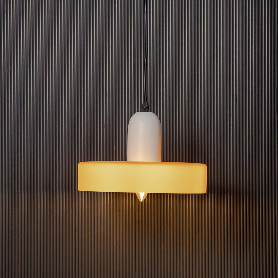 White and mustard yellow pendant ceiling light glowing warmly against dark black background creating luxury home decor look.