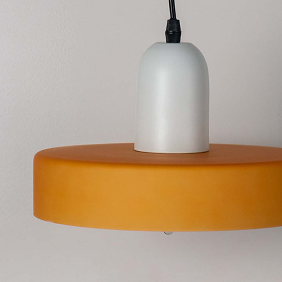 Closeup of white and mustard yellow pendant ceiling light showing smooth glossy finish and contemporary modern interior style.