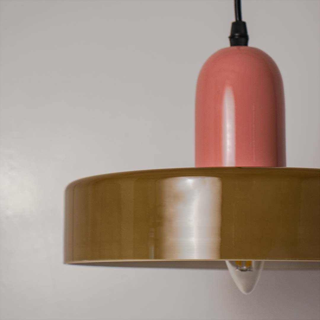 Pink metal pendant light with brass band and layered shade crafted for elegant modern spaces.