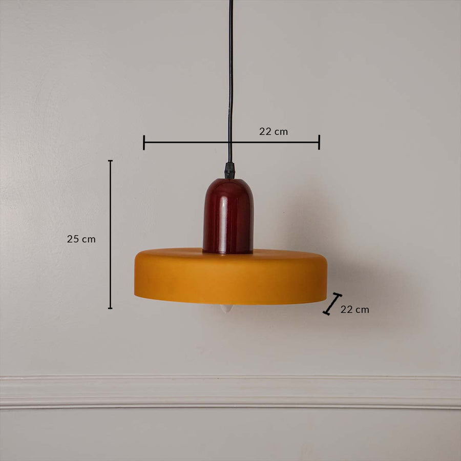 Mustard yellow and red pendant ceiling light with height 25 cm and width 22 cm shown clearly against plain off white background.