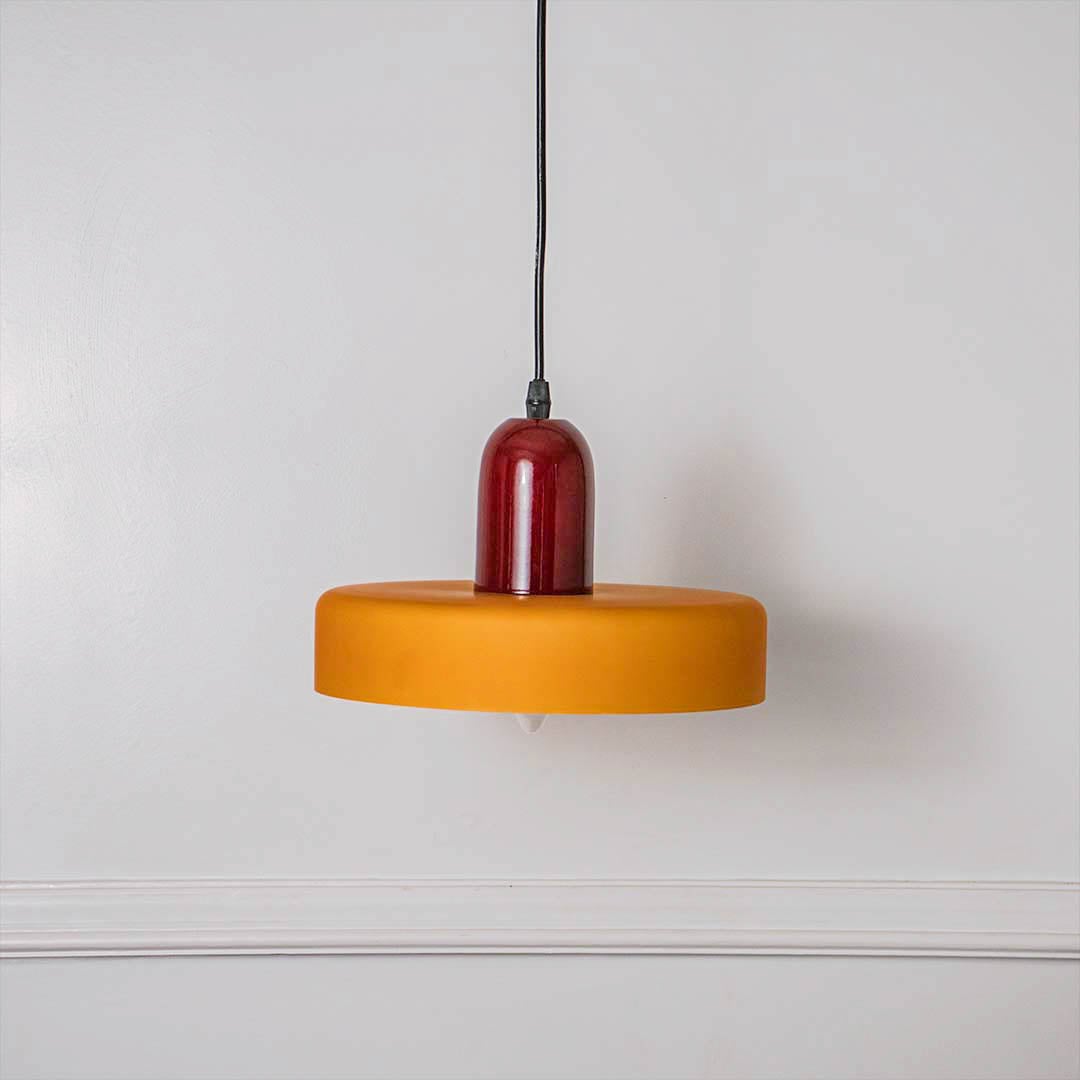 Contemporary mustard yellow and red round pendant ceiling light presented on minimal off white background for stylish interiors.