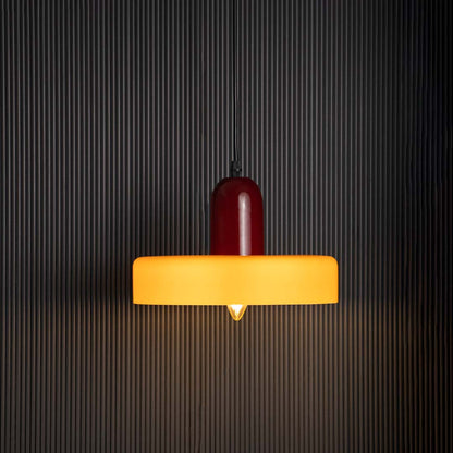 Mustard yellow and red pendant ceiling light glowing beautifully against dark black background creating modern decorative style.