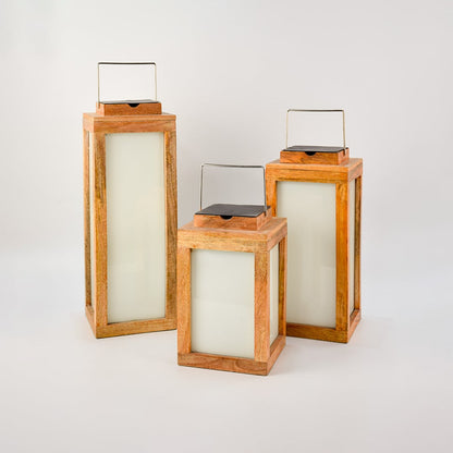 Set of three wood lanterns in different sizes with metal handles crafted from natural wood and frosted glass.