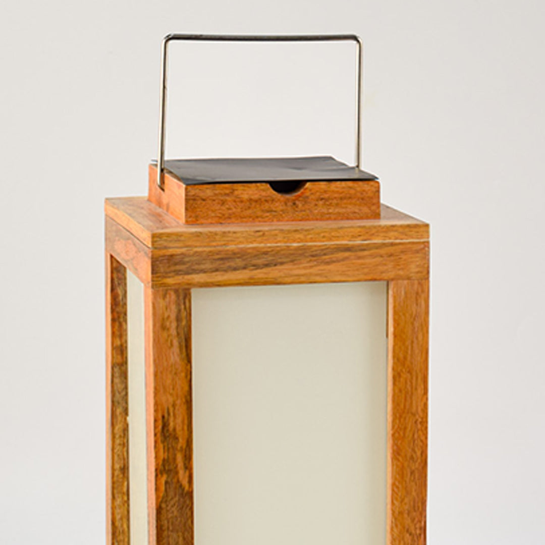Closeup of wooden lantern with frosted glass panels and metal handle for rustic decor styling use.