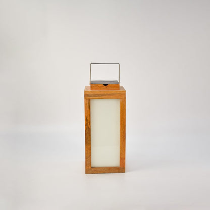 Wood lantern glowing on a white background showing its frosted glass panel illumination and premium wood craftsmanship — a modern decorative lighting piece.