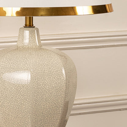 Beige textured lamp on console table with light on and cream wall background for soft warm décor.