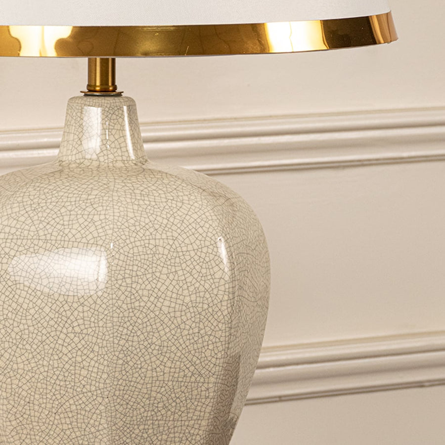 Beige textured lamp on console table with light on and cream wall background for soft warm décor.
