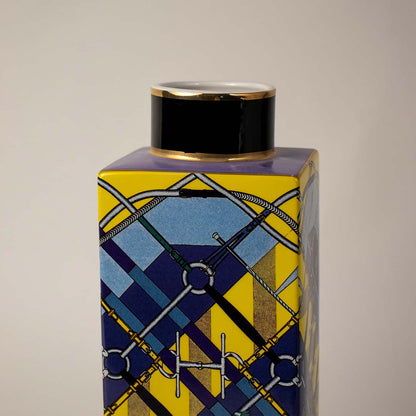 Closeup image ceramic jar vase with bold blue and yellow geometric pattern and black lid stylish modern home decoration.