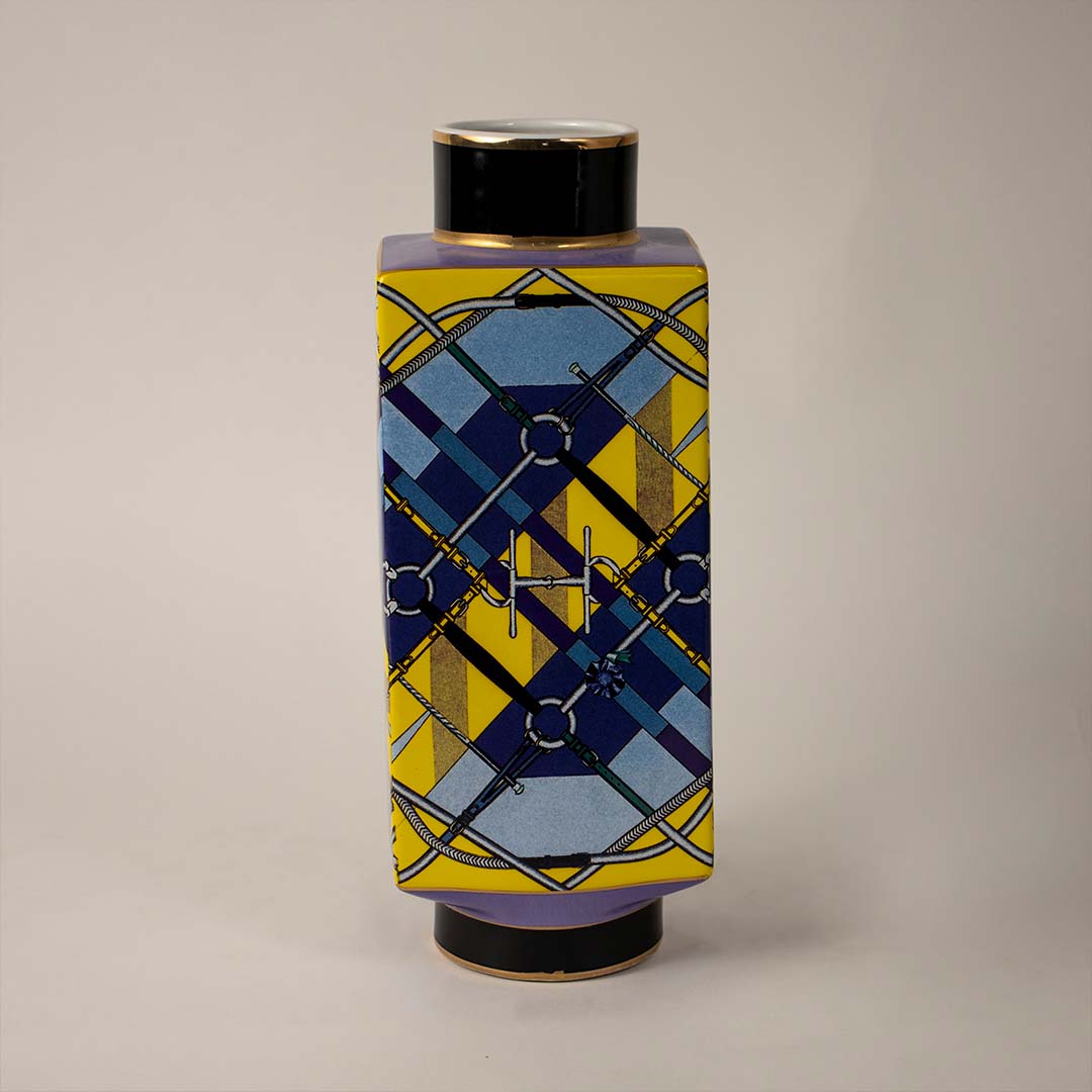 White background image ceramic decorative jar vase with geometric blue and yellow design and black lid perfect decor.