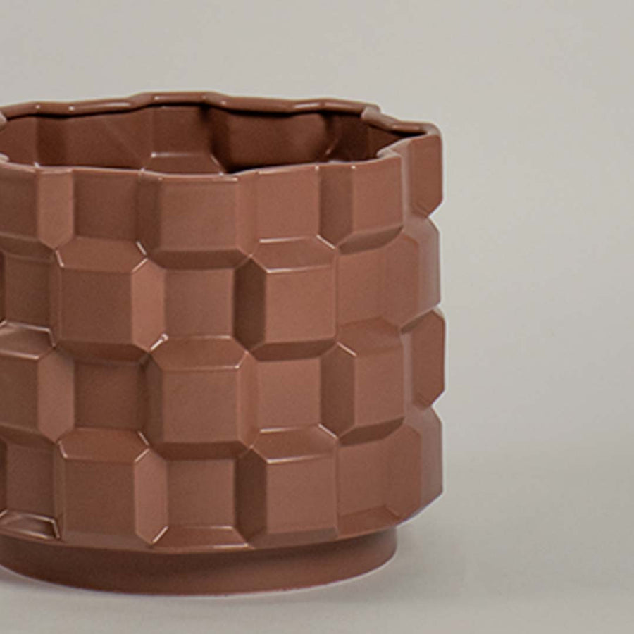 Closeup of brown ceramic planter showing its bold geometric textured pattern and glossy finish ideal for modern artistic home styling.