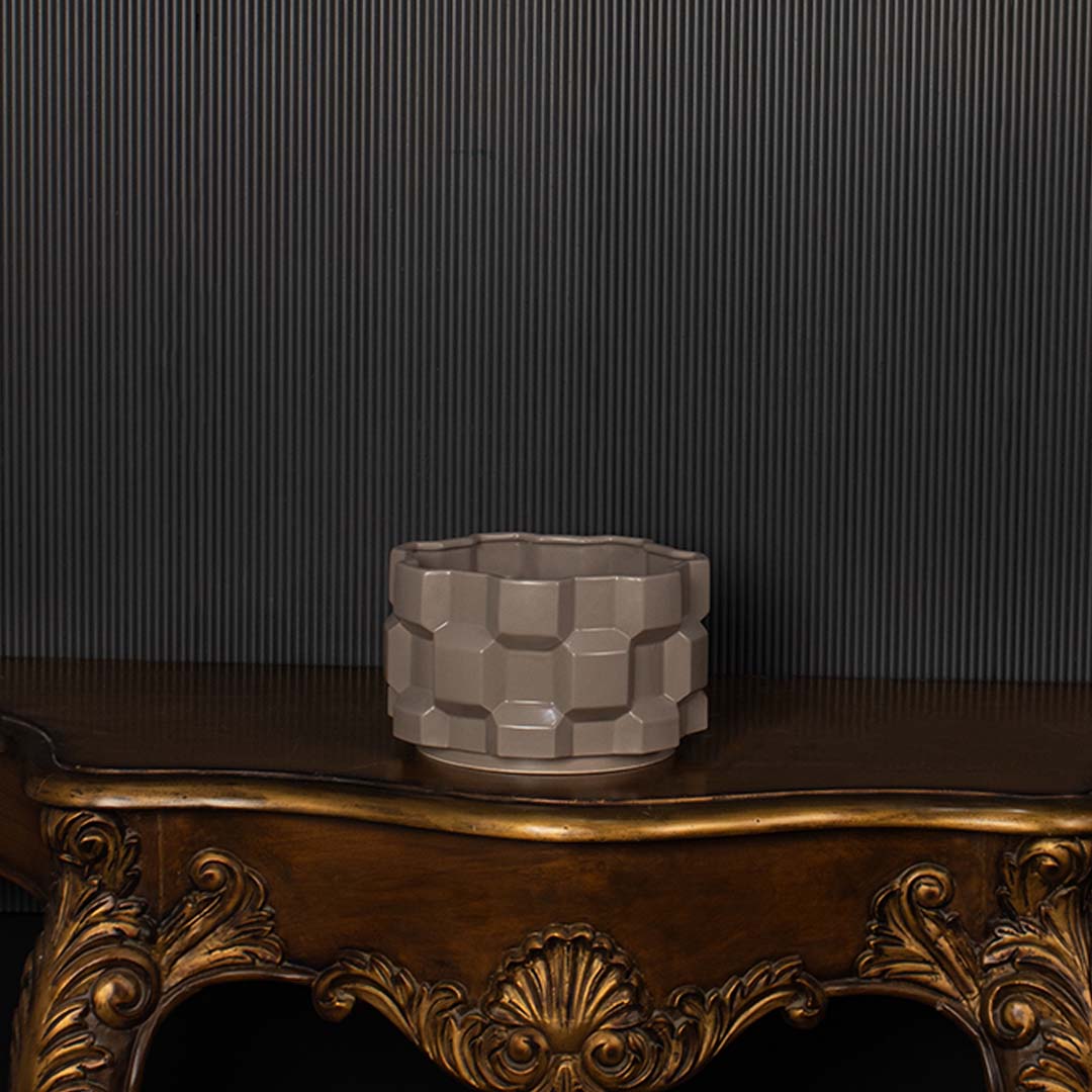 Geometric ceramic planter shown against a dark background creating a bold contrast and spotlighting its textured design.