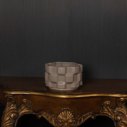 Geometric ceramic planter shown against a dark background creating a bold contrast and spotlighting its textured design.