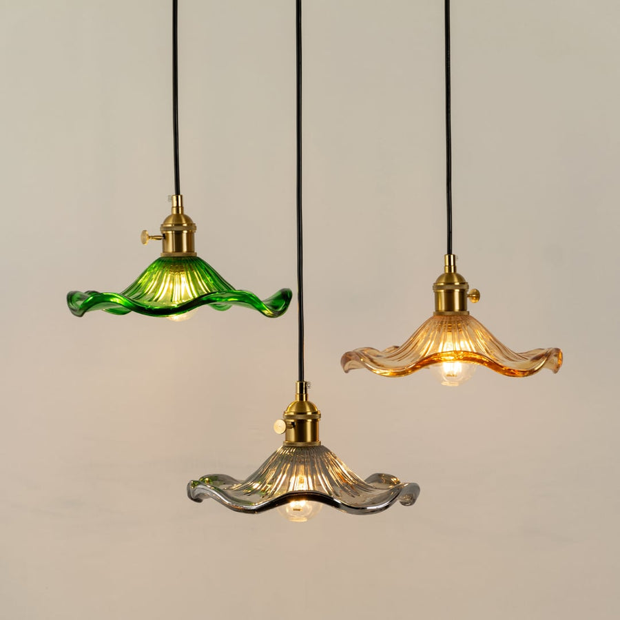 Green amber and clear glass pendant lights illuminated to display sophisticated decorative ceiling lighting elegance.