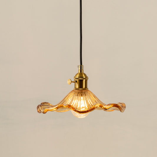 Pendant light with amber glass shade and gold holder emitting warm glow ideal for kitchen or dining decor on clean background.