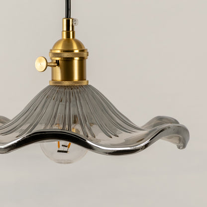 Closeup of clear glass pendant light with gold metal fitting highlighting elegant design for modern interior lighting decor styling.