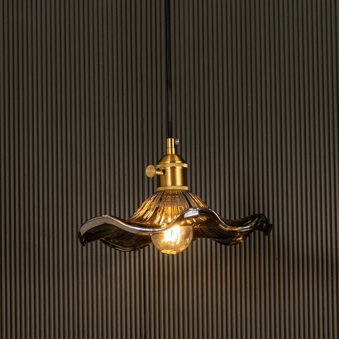 Wavy smoked glass pendant light with a polished metal holder casting soft ambient glow imagined against a dark background creating a dramatic refined interior decor mood.