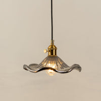 Clear textured glass pendant light with gold metal fixture illuminated to display elegant decorative ceiling lighting.