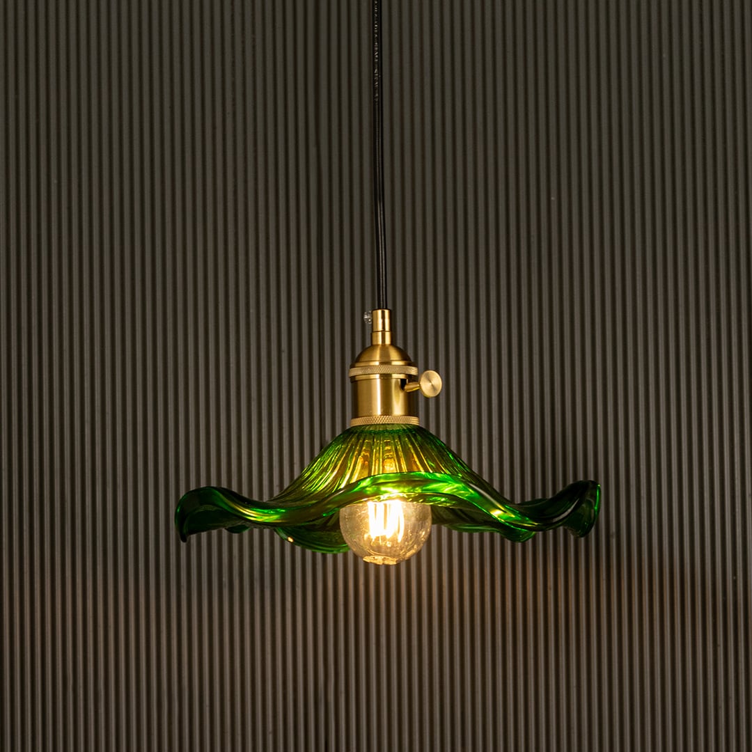 Green wavy glass pendant light with polished metal holder casting soft ambient glow imagined against a dark background creating a dramatic vibrant interior decor mood.