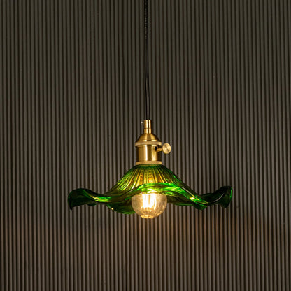 Green wavy glass pendant light with polished metal holder casting soft ambient glow imagined against a dark background creating a dramatic vibrant interior decor mood.