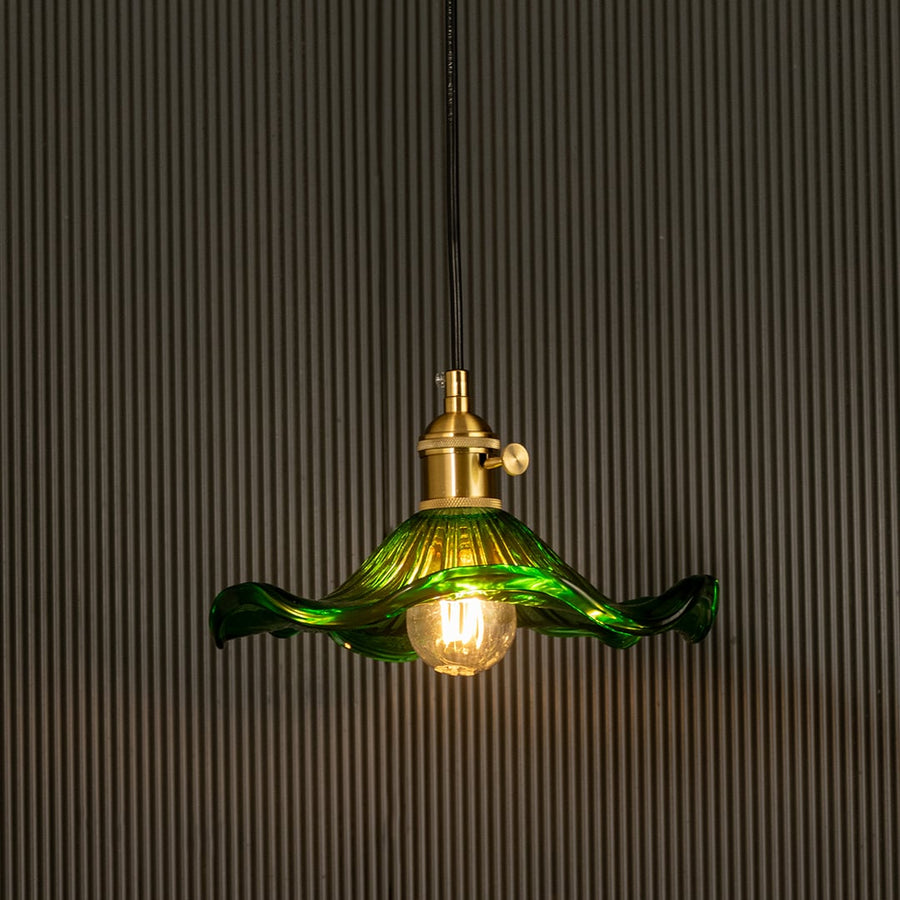 Green wavy glass pendant light with polished metal holder casting soft ambient glow imagined against a dark background creating a dramatic vibrant interior decor mood.