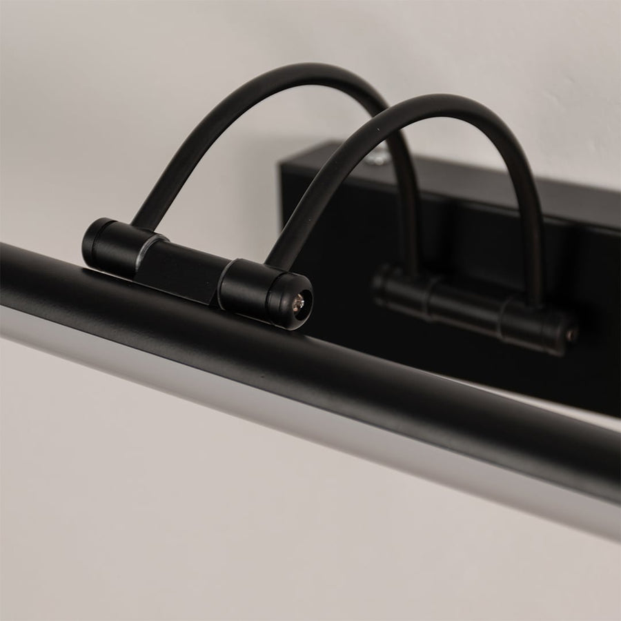 Closeup of the black metal picture light showing its adjustable arm and slim bar design for focused wall lighting.