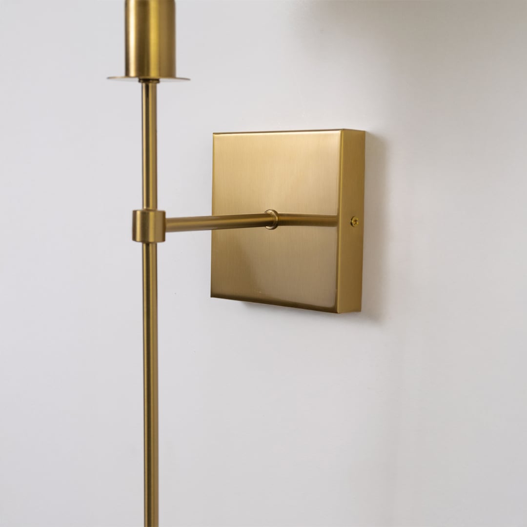 Closeup of gold wall sconce with beige shade showing refined fabric texture and premium modern lighting design.