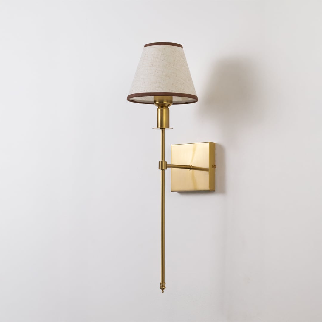 Gold metal wall sconce with beige fabric shade shown switched off on white background for minimal elegant wall decor.