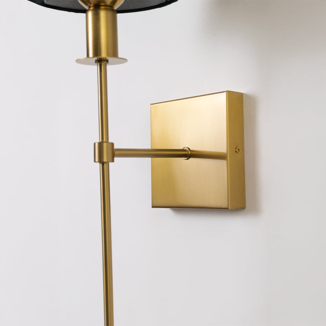 Closeup of gold metal wall sconce with black fabric shade showing refined detailing and premium contemporary design.