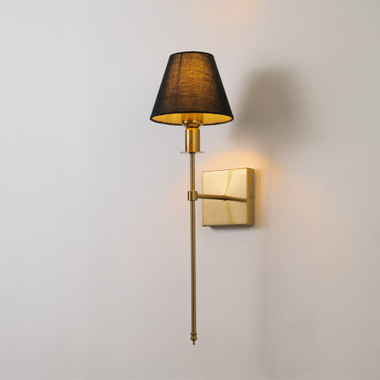 Contemporary wall light in gold metal finish with dark fabric shade for bedroom or living decor lighting white background.