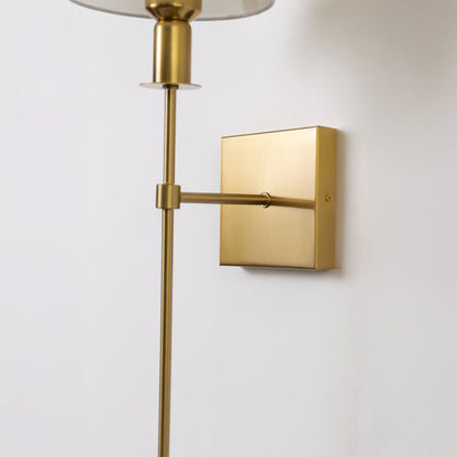 Closeup of gold metal wall sconce with white fabric shade showing refined detailing and premium contemporary design.