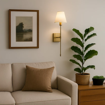 Gold metal wall sconce with tall white fabric shade styled in a modern room adding warm soft glow for elegant wall decor.