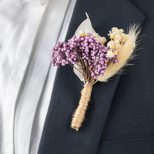 Closeup view of groom suit boutonniere featuring purple artificial flower with jute wrap perfect for stylish wedding decor.