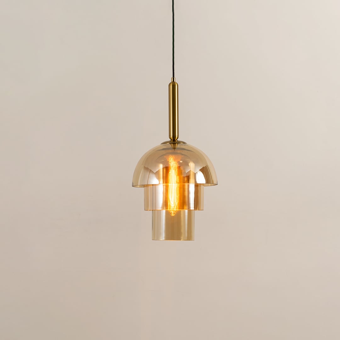 A gold glass pendant light displayed with lights on against a white background showcasing its layered dome design and warm glowing illumination.